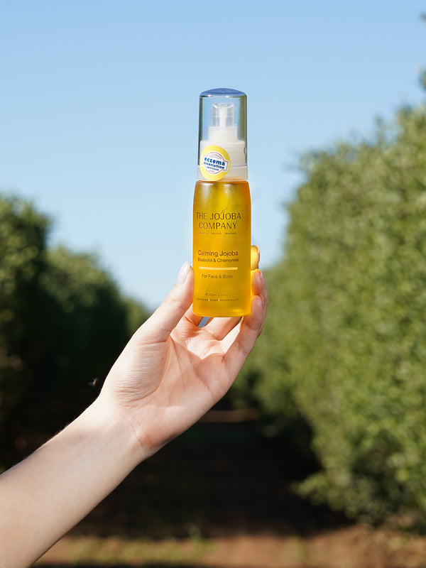 Hand holding a bottle of The Jojoba Company Calming Jojoba