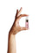Hand holding a miniature lilac Neck & Decolletage Lifting Concentrate bottle between thumb and fingertips, showing its small size and gold pump under a clear cap.
