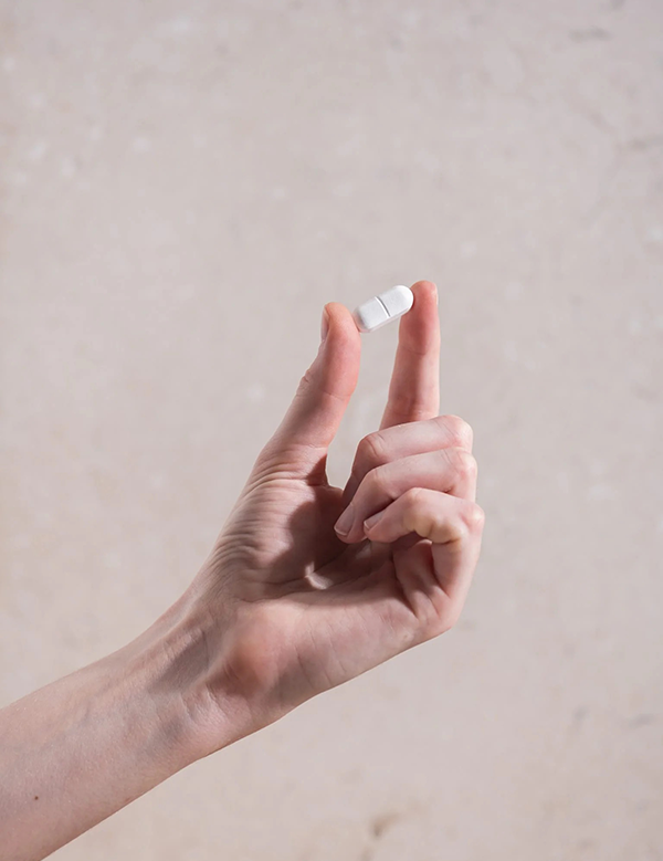 Hand holding a Herbs of Gold Magnesium Forte tablet