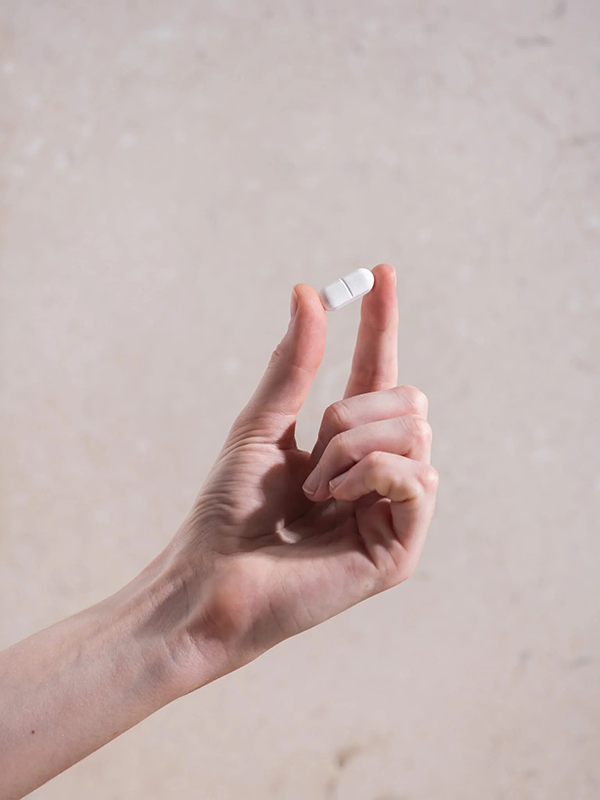 Hand holding a Herbs of Gold Magnesium Forte tablet