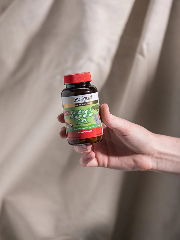 Hand holding the Herbs of Gold Children's Magnesium Care bottle
