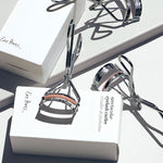 Two Ere Perez Spectacular Eyelash Curlers with their boxes on a white background