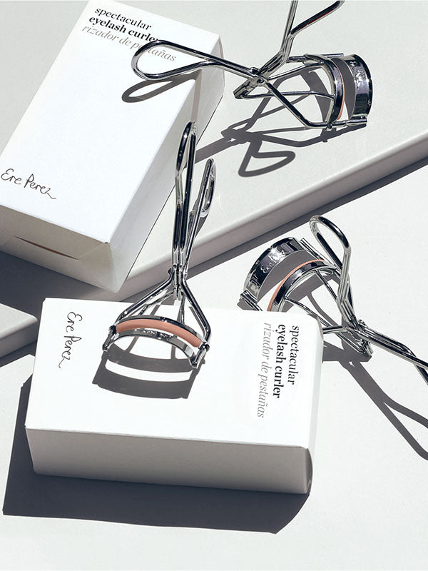 Two Ere Perez Spectacular Eyelash Curlers with their boxes on a white background