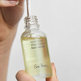 Hands lifting the dropper from an open bottle of Ere Perez Australian Blue Cypress Face Nectar