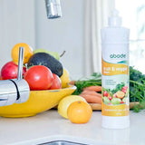 Abode Fruit and Vegetable Wash bottle at the kitchen sink beside a bowl of fresh produce
