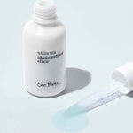 Ere Perez White Tea Phyto-Retinol Elixir open bottle with dropper and a drop of serum on a pale blue background