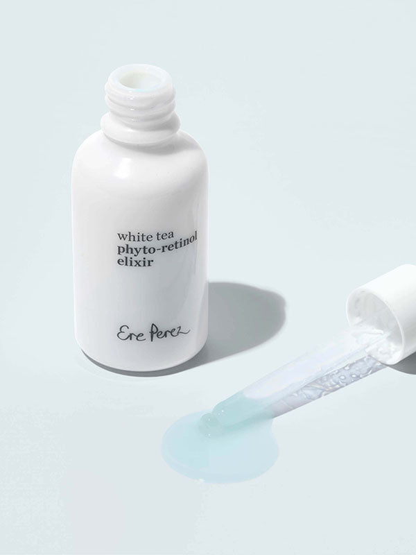 Ere Perez White Tea Phyto-Retinol Elixir open bottle with dropper and a drop of serum on a pale blue background