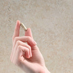 Hand holding a single Herbs of Gold Resveratrol AdvantAGE capsule