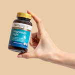 Hand holding the Herbs of Gold Magnesium Night bottle