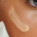 A close-up of a person’s cheek with a swipe of Avocado Zinc SPF 50 Natural Tinted Moisturiser 50ml. The skin looks smooth and glowing, with part of the cream tube showing. “Light” appears near the bottom.