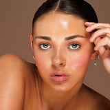 Model wearing Avocado Zinc SPF50 Natural Lip & Cheek Tint in Berry and holding the tint beside her face.