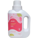 A 1-liter white bottle of Abode Laundry Liquid Baby with a pink label, handle, and measuring cap. This gentle, high-performance formula is specially made for sensitive skin.