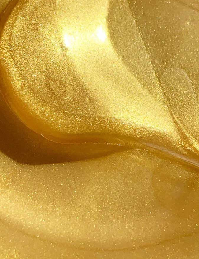 Close-up of a shiny, swirling golden liquid with a smooth texture and glimmering highlights, reminiscent of the luminous appearance of Acure Radically Rejuvenating Under Eye Hydrogels 4g.