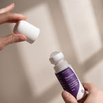 Hands removing the white cap from Amazing You Sleep Magnesium Gel 60ml, showing the roller ball and purple label in natural sunlight.