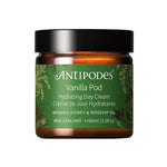 A brown jar with a black lid labeled Antipodes Vanilla Pod Hydrating Day Cream contains 50ml, features antioxidants like Manuka Honey and rosehip oil, and displays a green botanical label. Made in New Zealand.