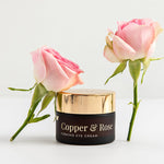Vanessa Megan Copper and Rose Firming Eye Cream jar with fresh roses