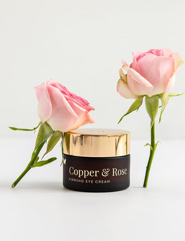 Vanessa Megan Copper and Rose Firming Eye Cream jar with fresh roses
