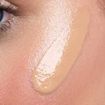 A close-up of a person's cheek with a swatch of Avocado Zinc SPF50 Physical Bronzing Drops 40ml applied, highlighting the texture and coverage on the skin near the eye.