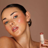 Model wearing Avocado Zinc SPF50 Natural Lip & Cheek Tint in Nude and holding the tint beside her face.