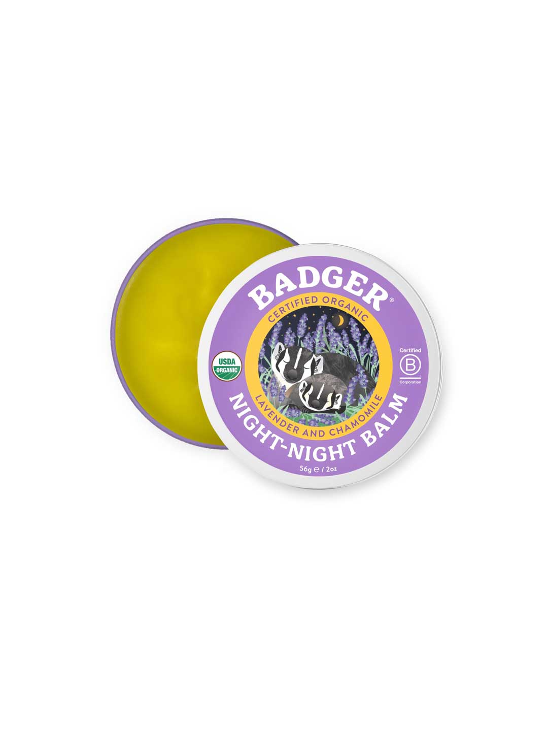 A 56g tin of Badger Night Night Balm with the lid partly off reveals yellow balm inside. The purple lid shows a badger illustration and reads "Lavender and Chamomile Night Night Balm," an organic children’s bedtime balm.