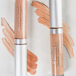 Two tubes of Benecos Concealer 5ml stand upright on a white background, with swatches of this long-lasting formula in various shades displayed beside each tube.