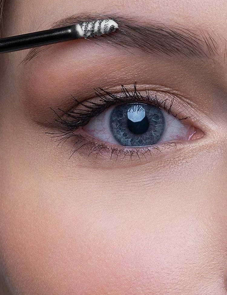 Close-up of a person's blue eye and well-groomed brows as Benecos Eyebrow Gel 3ml is applied with a makeup brush to shape and fill in the eyebrow.