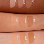 Three forearms of different skin tones display swatches of Benecos Natural Foundation Stick 6g in ivory, sand, and tan, demonstrating the buildable coverage these vegan shades offer across various complexions.