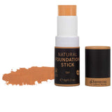 The Benecos Natural Foundation Stick 6g in tan is displayed with the cap off, revealing the product and a swatch on the left. The cap lies nearby, emphasizing its buildable coverage and organic formula.
