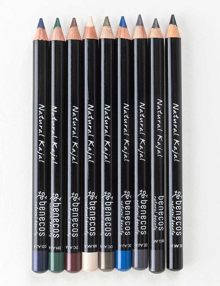 Eight Benecos Kajal Eyeliner 1.13g pencils in assorted colors are arranged side by side on a light background, their sharpened tips pointing upward. Each pencil features label details and color indicators at the base.