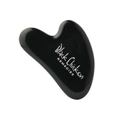 The Black Chicken Remedies Black Obsidian Gua Sha is a sleek black facial massage tool with the brand name in white text, inspired by Traditional Chinese Medicine and shown against a plain white background.