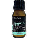 A 30g brown bottle of Black Chicken Remedies Complexion Polish features a black cap and a black, teal, and white label, highlighting its 100% natural rice powder gentle scrub formula.