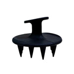 The Black Chicken Remedies HairOM Scalp Brush is a black handheld brush with a round base, ergonomic top handle, and short, pointed silicone bristles for effective hair care and soothing scalp massages.