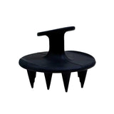 The Black Chicken Remedies HairOM Scalp Brush is a black handheld brush with a round base, ergonomic top handle, and short, pointed silicone bristles for effective hair care and soothing scalp massages.