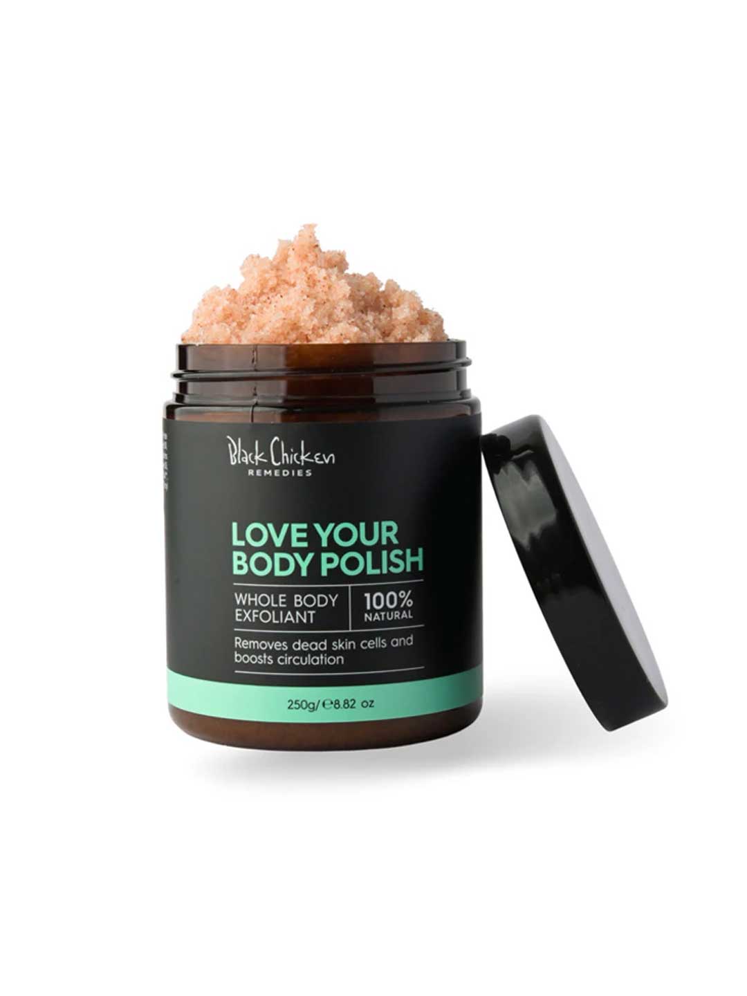 A jar of Black Chicken Remedies Love Your Body Polish Natural Body Scrub 250g with the lid open reveals a pink, granular scrub made with Himalayan Pink Salt for gentle exfoliation; the label states it is 100% natural.