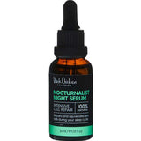 A bottle of Black Chicken Remedies Nocturnalist Night Serum 30ml with a dropper stands before a Jack Daniels bottle, fusing the vibrance of nightlife with luxurious natural skincare.