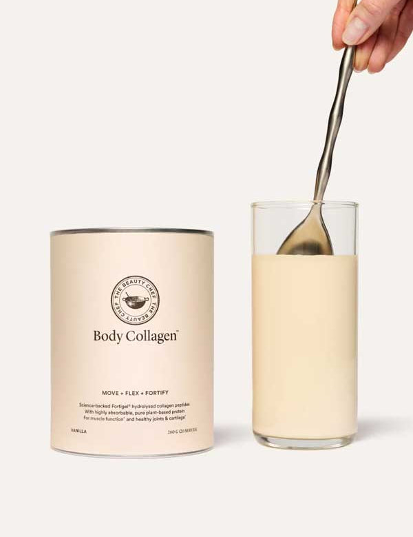 A hand stirs a creamy beige drink next to a The Beauty Chef Body Collagen™ Vanilla 260g container, showcasing the nourishing benefits of collagen peptides.