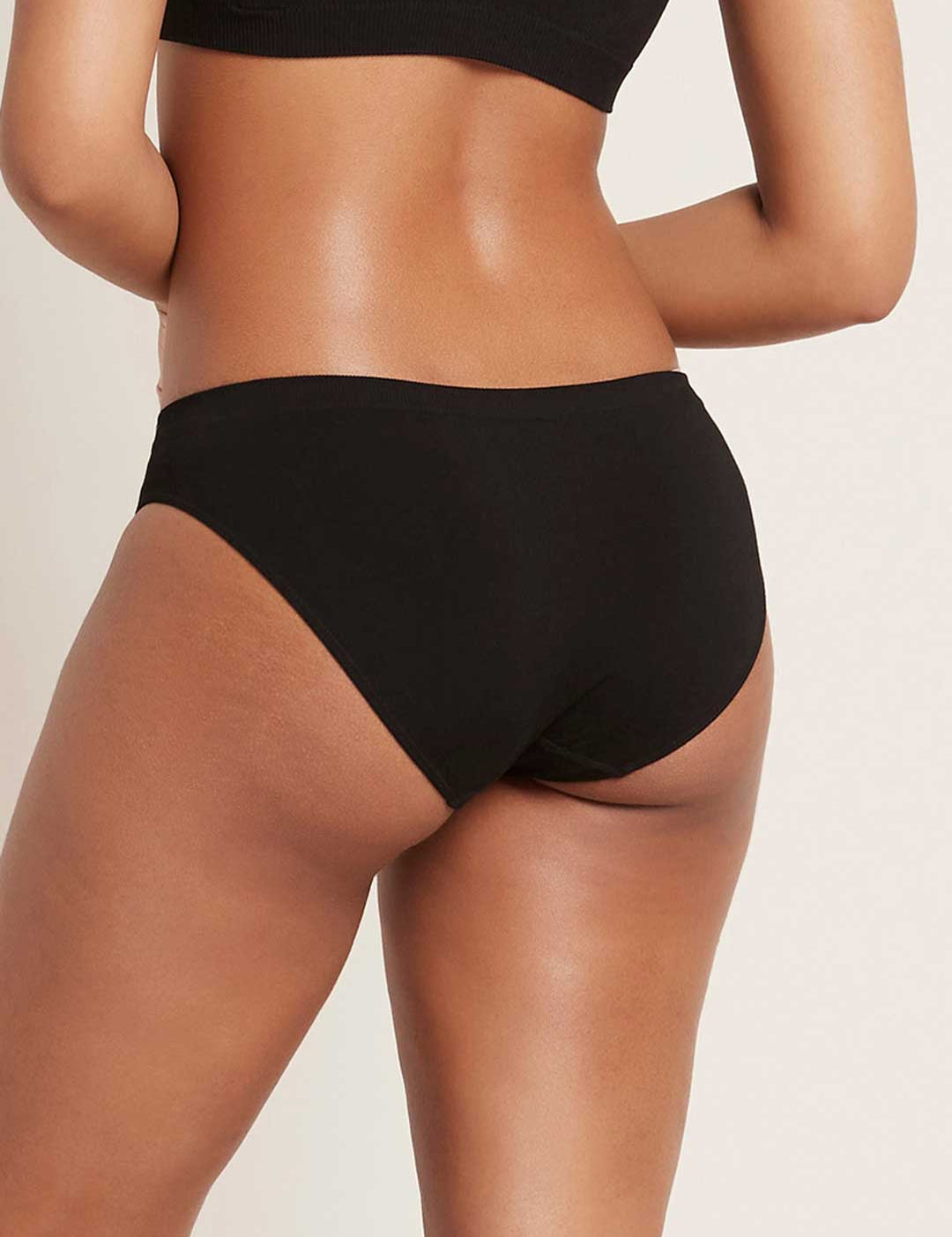 Rear view of a model wearing black Boody Classic Bikini briefs, showing the low waistband and curved leg openings.
