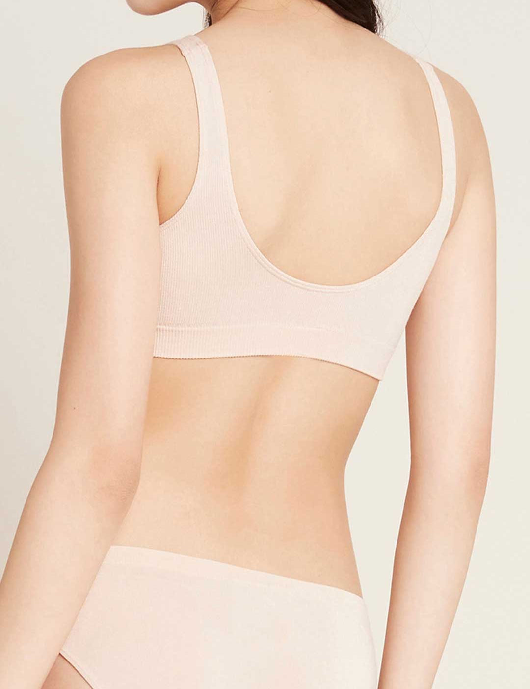 Rear view of a model wearing a pale blush-beige Boody Seamfree Crop Bra in Shell, showing broad straps, a deep rounded back and a wide band.