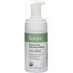 A 100ml bottle of Botani Rescue Acne Foaming Cleanser features a pump dispenser and a green-white label highlighting salicylic acid. Vegan and cruelty-free icons emphasize this natural face wash.