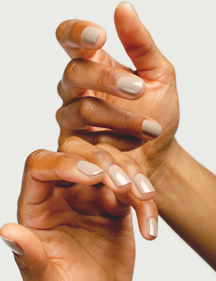 A close-up of two hands with neatly manicured nails painted in Sienna Byron Bay Nail Polish - Calm 10ml, a warm clay shade that looks elegant and subtle, posed gracefully against a plain light background.