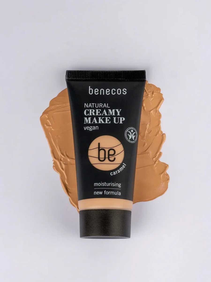 A 30ml tube of Benecos Natural Creamy Makeup stands upright on a matching smear, with product details and vegan makeup label clearly visible.