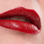 Close-up of glossy red lips wearing Benecos Natural Lipsticks 4.5g, highly pigmented and slightly parted to show a hint of teeth. The background and skin are neutral, with "Cat Walk" displayed at the bottom.