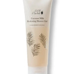A pale beige 100% Pure Coconut Milk Hydrating Shower Gel tube stands on a translucent flip-top cap. Fine dark palm-frond drawings decorate the front below the product name.