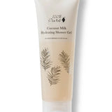 A pale beige 100% Pure Coconut Milk Hydrating Shower Gel tube stands on a translucent flip-top cap. Fine dark palm-frond drawings decorate the front below the product name.