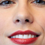 Close-up of a person's mouth and nose, showing smooth skin and lips with bright red Luk Beautifood Lip Nourish Lipsticks 3g made from food-grade ingredients. The text Cranberry Citrus appears in the bottom left corner.