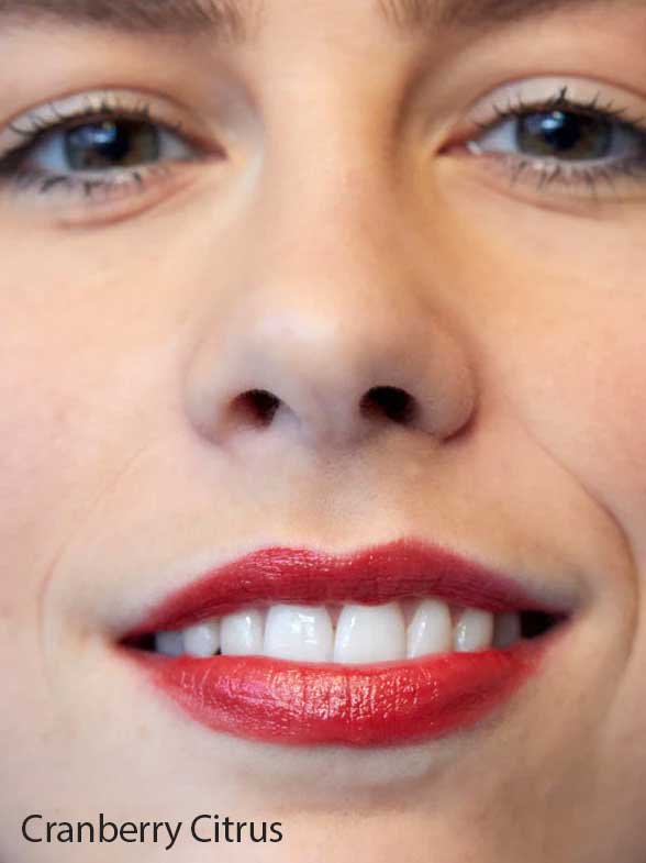 Close-up of a person's mouth and nose, showing smooth skin and lips with bright red Luk Beautifood Lip Nourish Lipsticks 3g made from food-grade ingredients. The text Cranberry Citrus appears in the bottom left corner.