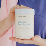 A person in a purple shirt holds a Mister Jones Creatine Monohydrate 300g container, showcasing this pure creatine supplement designed to support strength, mood, and energy.