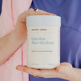 A person in a purple shirt holds a Mister Jones Creatine Monohydrate 300g container, showcasing this pure creatine supplement designed to support strength, mood, and energy.