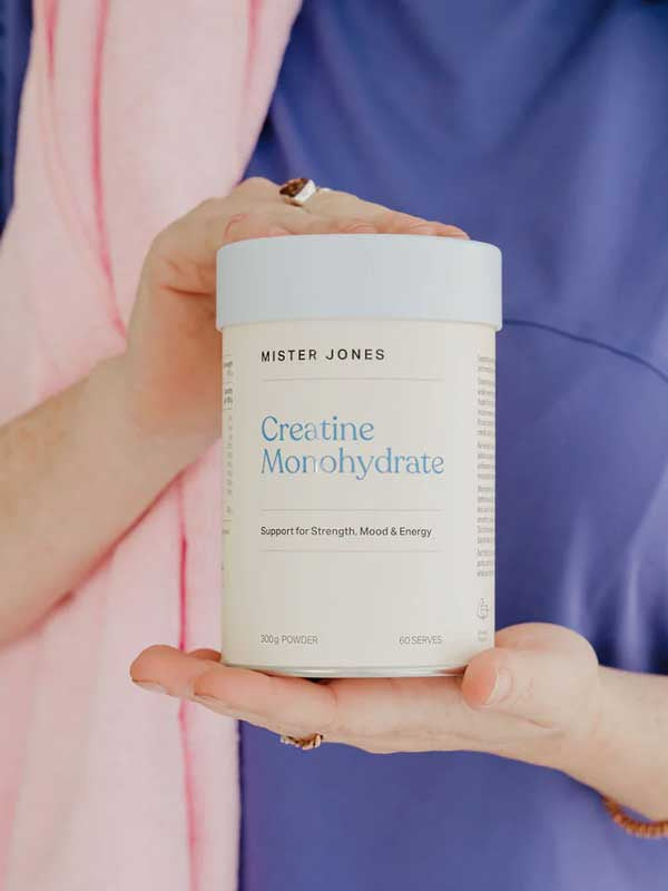 A person in a purple shirt holds a Mister Jones Creatine Monohydrate 300g container, showcasing this pure creatine supplement designed to support strength, mood, and energy.