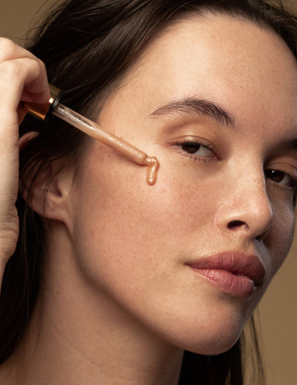 Model applying Antipodes Credo Probiotic Anti-Blemish Serum with a dropper